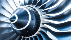 Close-up of a jet engine turbine with metallic blades, showcasing advanced engineering and precision manufacturing.